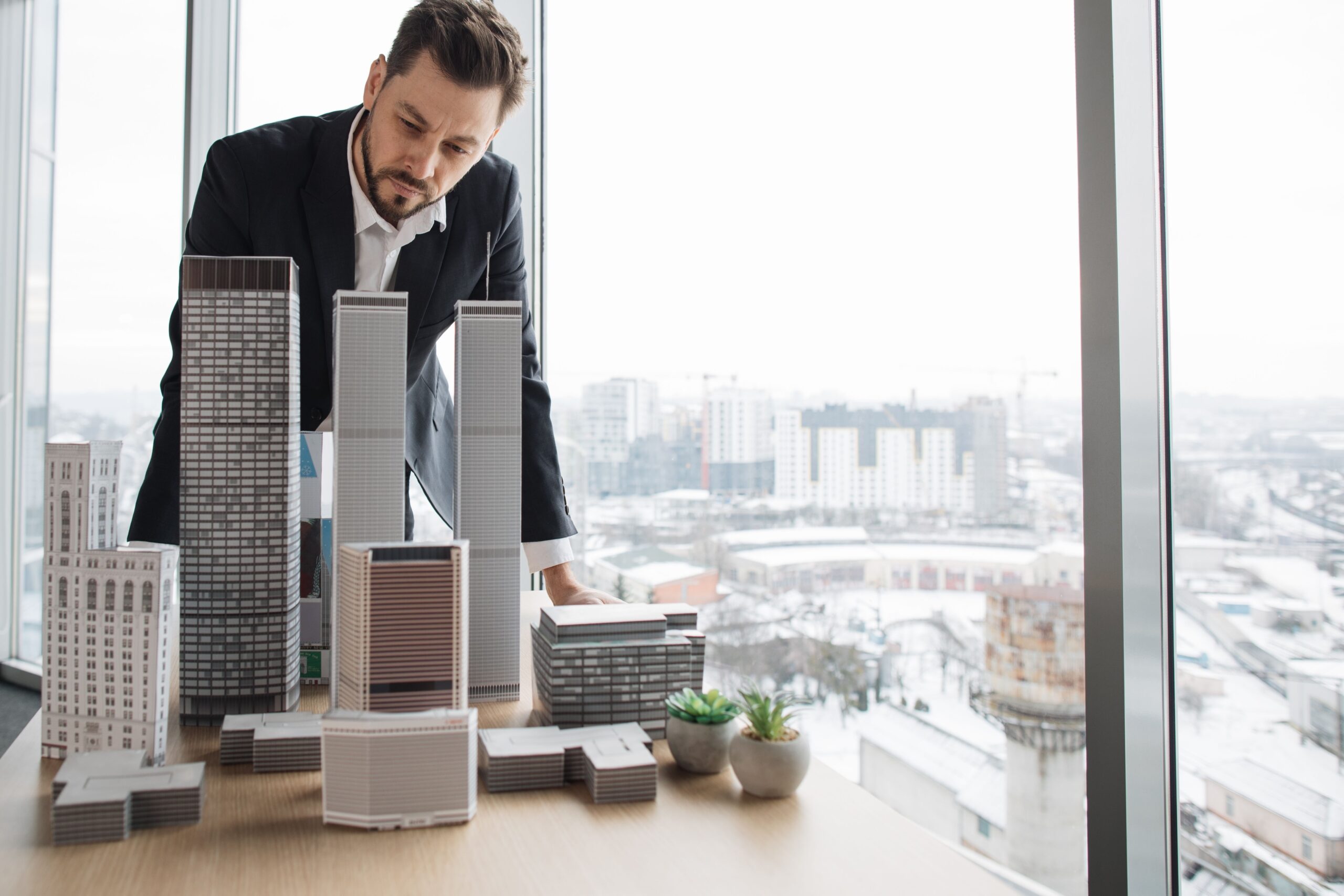 יזם בוחן מודלים של בניינים כחלק מתהליך בדיקת היתכנות ליזמי נדל״ן לפני השקעה